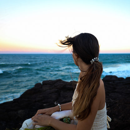 Woman sitting on rocks by the ocean at sunset