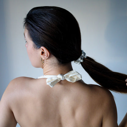 Woman with a pearl hair tie in her hair against a neutral background